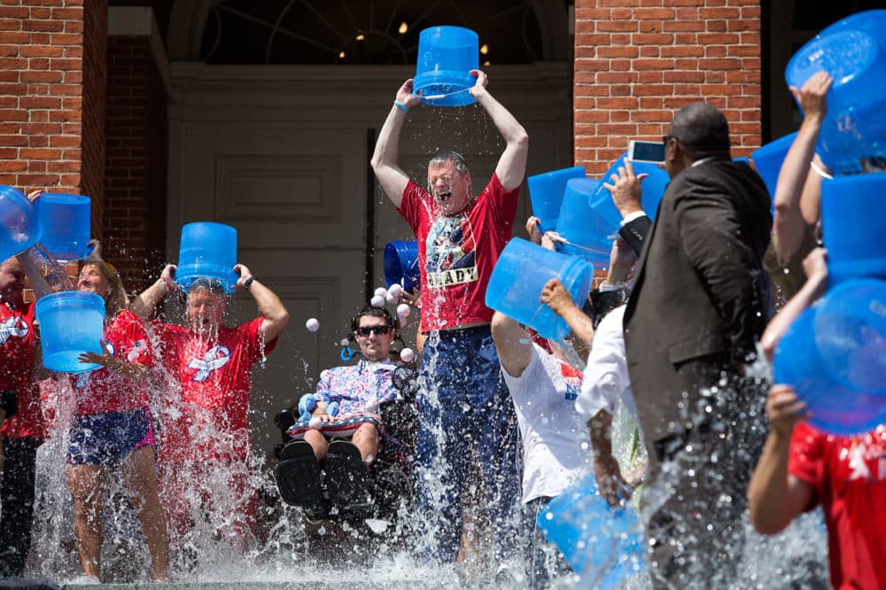 Gov. Charlie Baker and a crowd of people take the ALS Ice Bucket Challenge in 2015 as Pete Frates, center, looks on at the top of the State House steps. (Jesse Costa/WBUR)