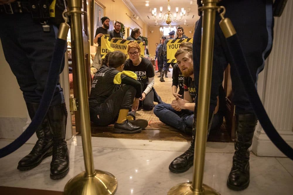 A group of climate protesters wait in the reception area of the governor's State House office. (Robin Lubbock/WBUR)