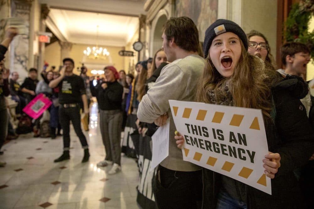 Climate protesters chanting and singing in the halls outside the Governor's Office in December 2019. (Robin Lubbock/WBUR)