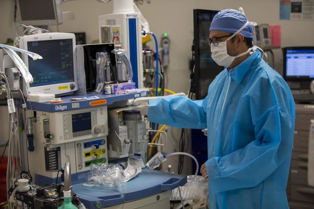 Mauricio Gonzalez, vice chair for clinical affairs at Boston Medical Center, reaches toward a canister of sevoflurane. (Jesse Costa/WBUR)