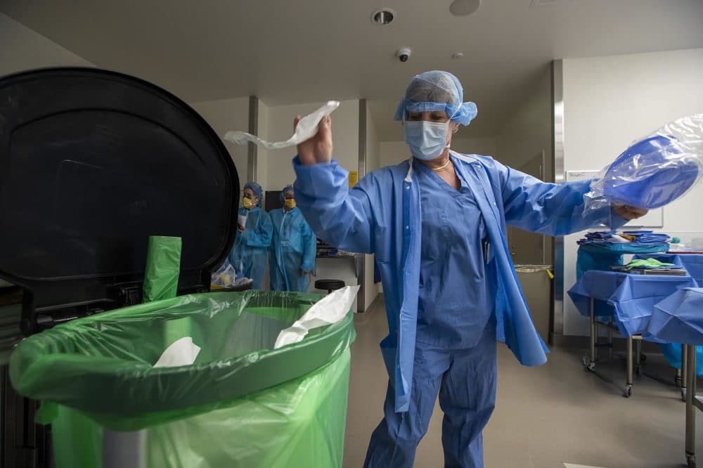 Polly Woodworth recycles a paper seal she just ripped from packaging of a sterile bowl. (Jesse Costa/WBUR)