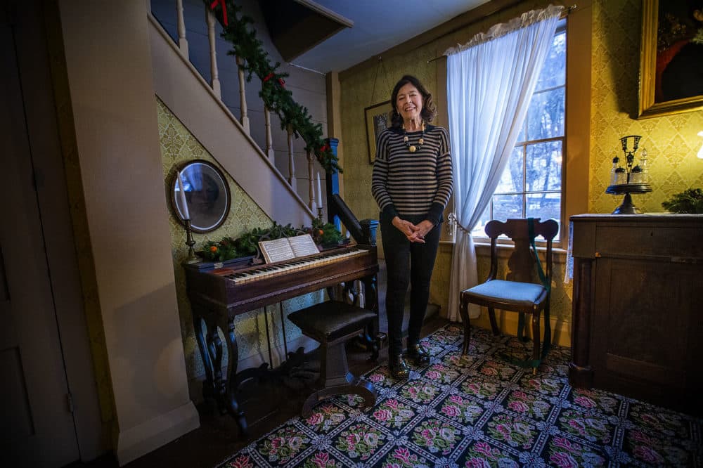Executive director of Orchard House Jan Turnquist stands by Louisa May Alcott's melodeon in the dining room. (Jesse Costa/WBUR)