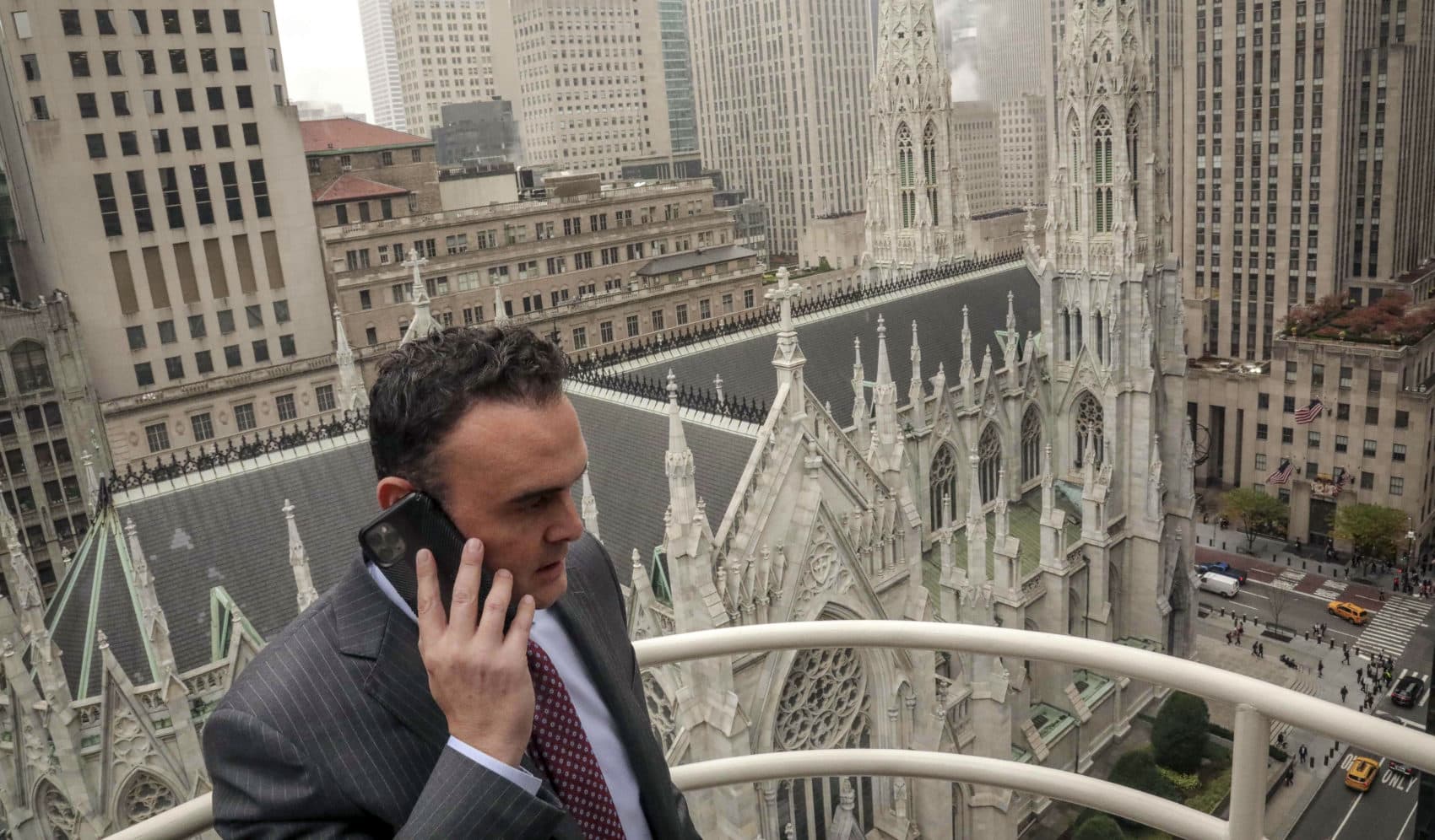 Attorney Adam Slater takes a phone call on a patio outside his high-rise Manhattan office overlooking St. Patrick's Cathedral, in New York. Slater's firm is representing clients accusing the Roman Catholic Church of sexual abuse. (Bebeto Matthews/AP)