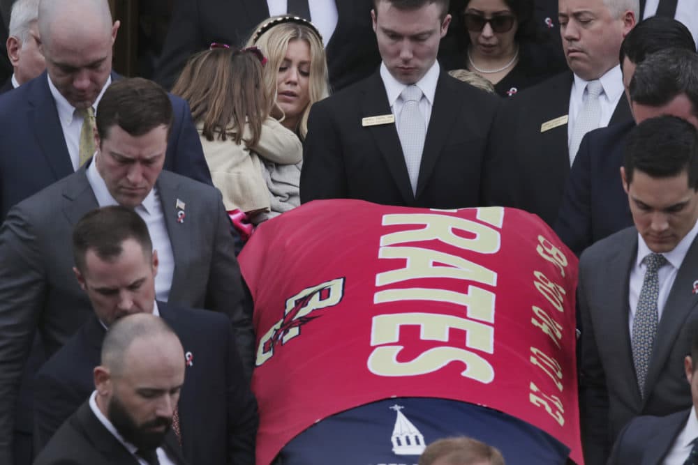 Julie Frates carries her daughter Lucy as they follow the casket of her husband Pete Frates following his funeral at St. Ignatius of Loyola Parish church at Boston College. (Charles Krupa/AP)
