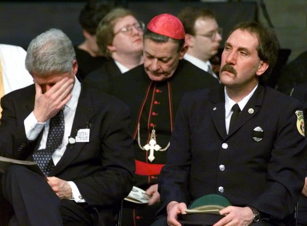 President Clinton puts his head in his hands as he sits with Frank Raffa, president of the Worcester Firefighters Union, far right, and an unidentified clergyman during the 1999 memorial service. (Stephan Savoia/AP)
