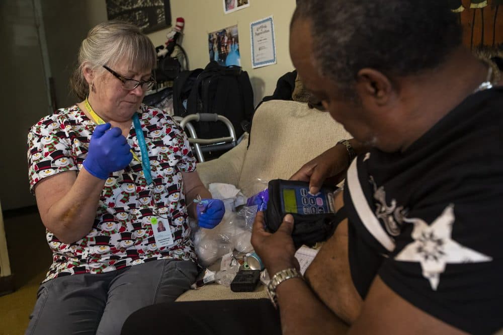 Brenda Mastricola checks on the PICC line through which Arthur Jackson, a former drug user, is receiving penicillin to treat a bone infection. (Jesse Costa/WBUR) 