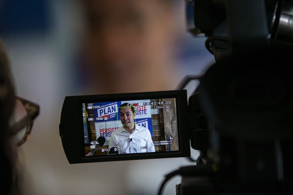 A videographer looks at her screen, as former presidential candidate Julian Castro, who is campaigning for Sen. Elizabeth Warren, speaks with reporters following a small gathering at La Carreta Mexican Grill in Marshalltown, Iowa. (Jesse Costa/WBUR)