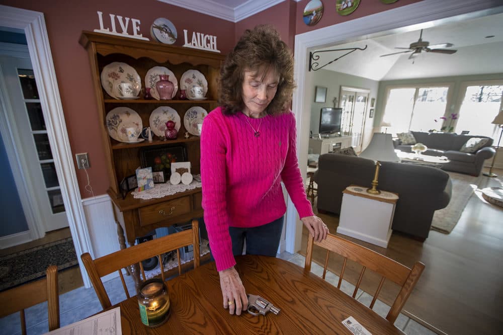 Cynthia English reaches for her Smith and Wesson revolver on the dining room table. (Jesse Costa/WBUR)