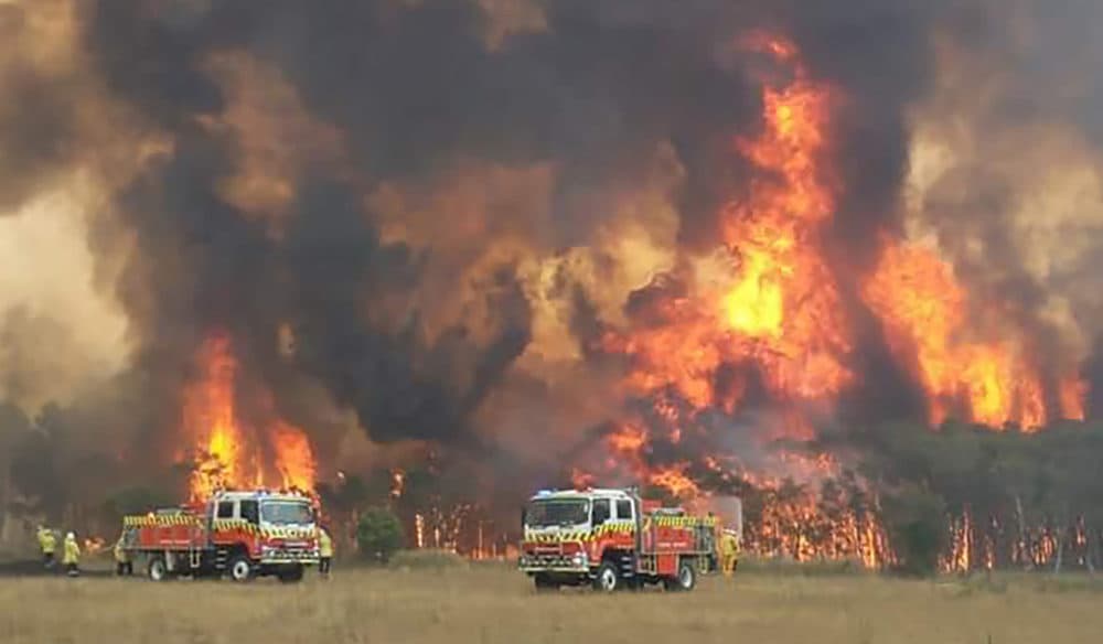 In this image dated Dec. 30, 2019, and provided by NSW Rural Fire Service, firefighters are seen as they try to protect homes around Charmhaven, New South Wales. (Twitter@NSWRFS via AP)