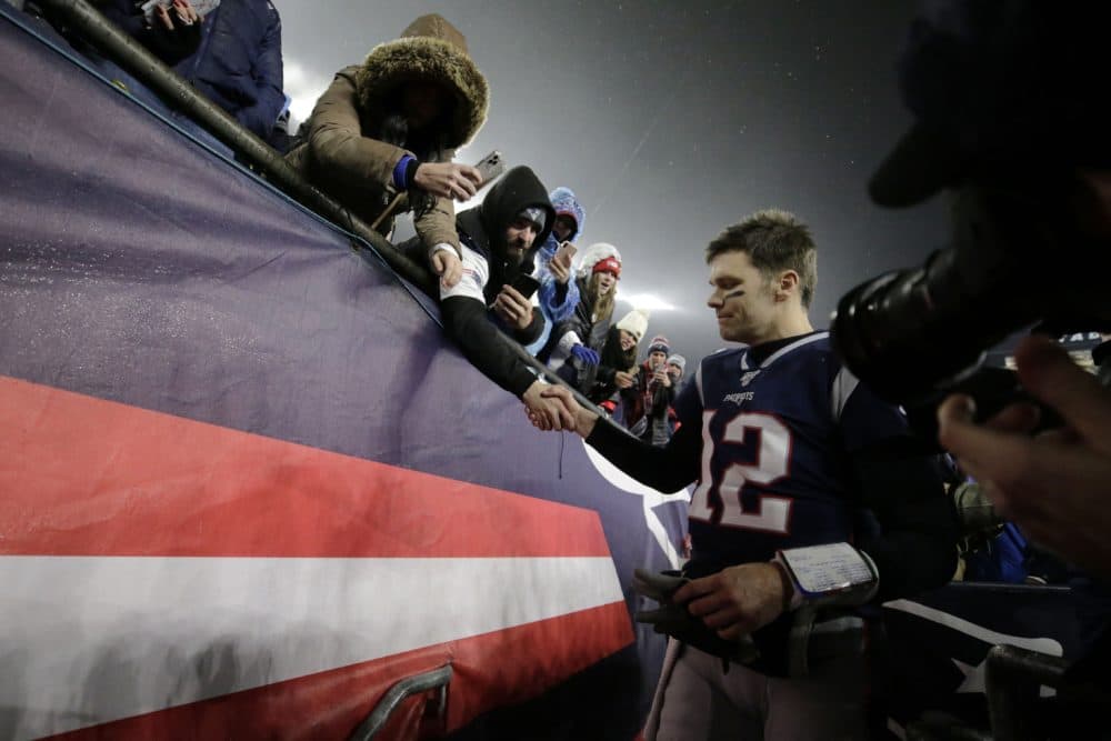 New England Patriots quarterback Tom Brady shakes hands with a fan as he leaves the field after a January 2020 loss. (Charles Krupa/AP)