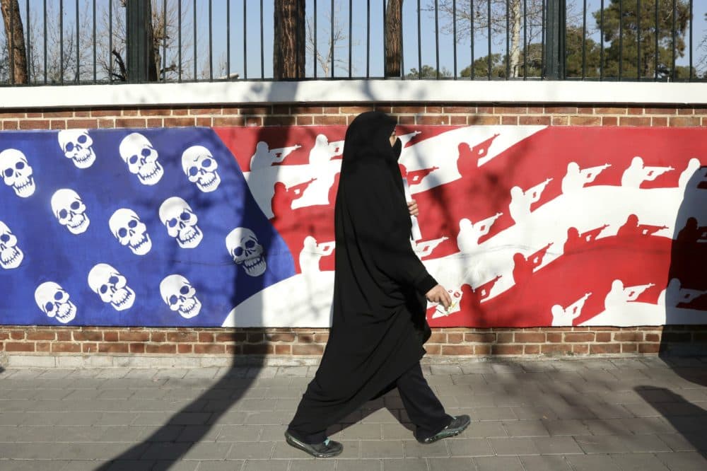 A mourner walk back from a funeral ceremony for Iranian Gen. Qassem Soleimani and his comrades, who were killed in Iraq in a U.S. drone attack on Friday, passing graffiti on the wall of the former U.S. Embassy in Tehran, Iran, Monday, Jan. 6, 2020. Funeral ceremonies for Soleimani drew a crowd said by police to be in the millions, on Monday in Tehran, where his replacement vowed to take revenge. (Vahid Salemi/AP)