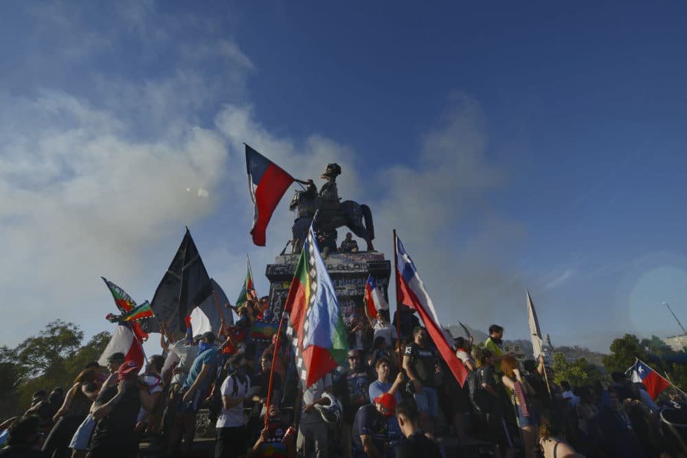 Protesters climb the statue of General Manuel Baquedano. (Jorge Sanchez for WBUR)