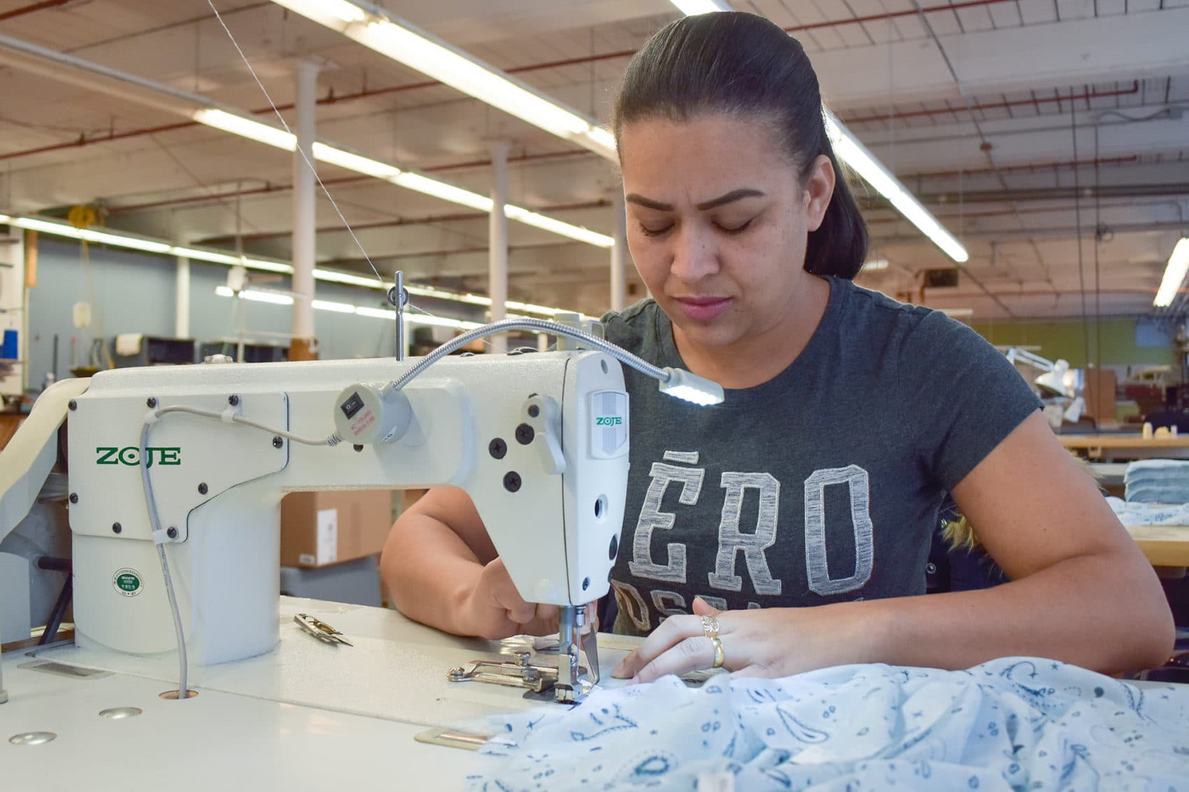 At Good Clothing Company in Fall River, Massachusetts, a seamstress uses a metal tool to work fabric. (Allison Hagan/Here & Now)