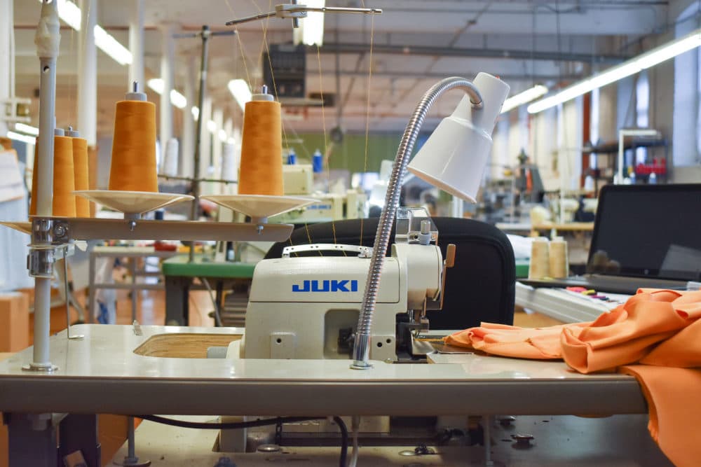 A sewing station complete with an industrial machine and large spools of thread at a clothing manufacturer in Fall River, Massachusetts. (Allison Hagan/Here &amp; Now)