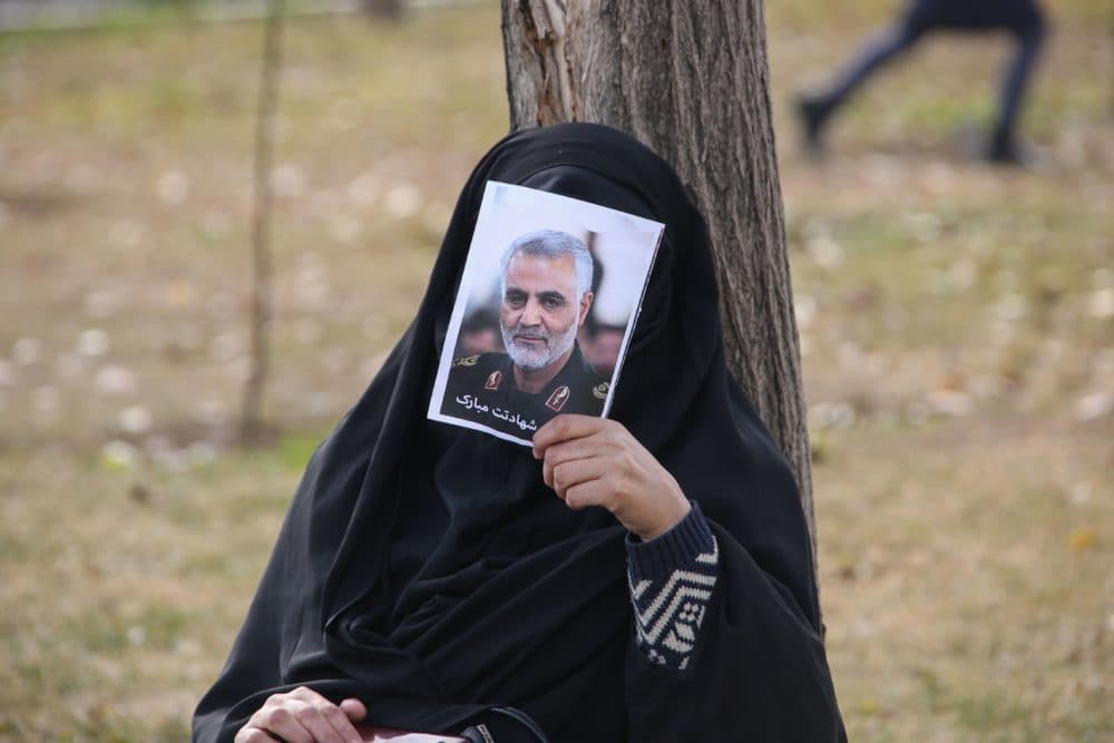 An Iranian woman covers her face with a picture of Iranian Maj. Gen. Qassem Soleimani during a demonstration in Tehran against the killing of the top commander in a U.S. strike in Baghdad. (Atta Kenare/AFP/Getty Images)