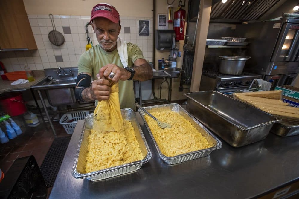 Cook Steve Cabral squeezes out macaroni and cheese for lunchtime guests at Father Bill’s Place in Quincy. He was a former guest at the shelter's sister facility, MainSpring House, in Brockton. (Jesse Costa/WBUR)
