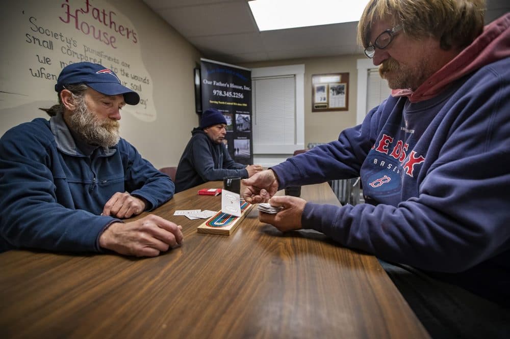 XXXX deals cards to XXXX as they play a hand of cribbage while they wait for dinner to be served at Our Father’s House in Fitchburg. (Jesse Costa/WBUR)