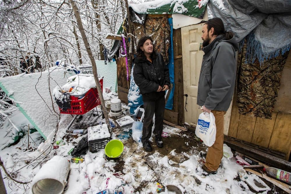 Evis Terpollari, right, checks with Monte Kelly, who is living in a shack in the woods he built using material he pulled from dumpsters. (Jesse Costa/WBUR)