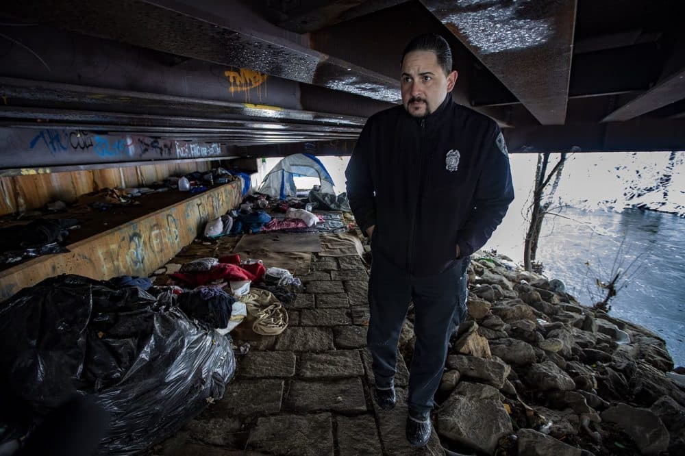 Worcester Police Officer Angel Rivera walks beneath a bridge along the Blackstone River where there is a homeless encampment. (Jesse Costa/WBUR)