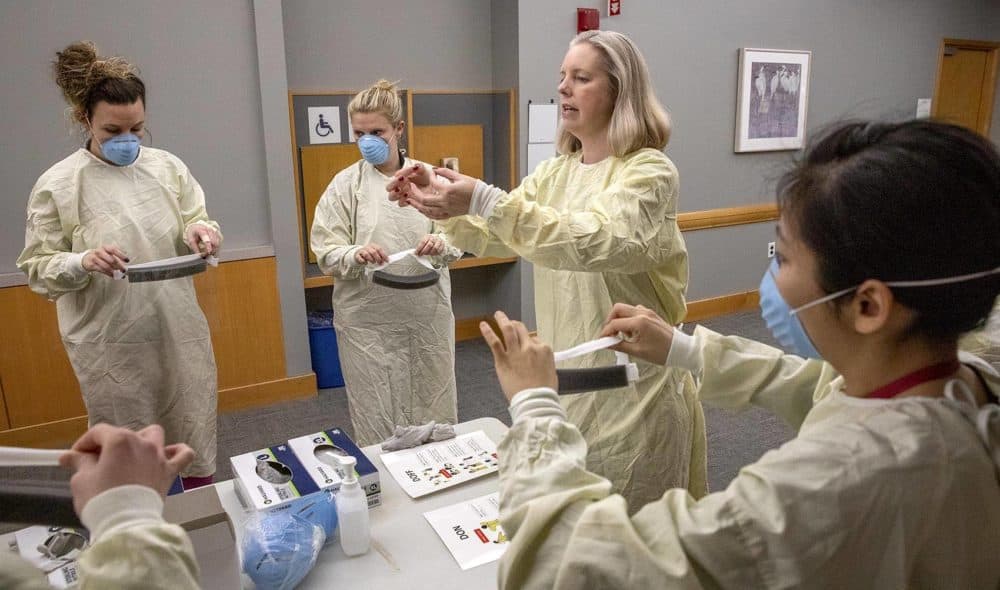 Janice McLaughlin demonstrates how to don and doff a medical visor during a training session on personal protective equipment at Tufts Medical Center. (Robin Lubbock/WBUR)