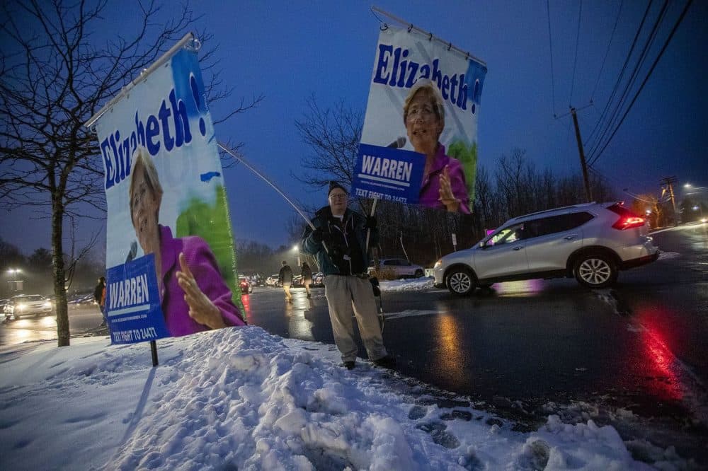 Edward Kimmel, of Tacoma Park, Md., holds up signs for a Warren campaign event outside of Tupelo Music Hall in Dover. (Jesse Costa/WBUR)