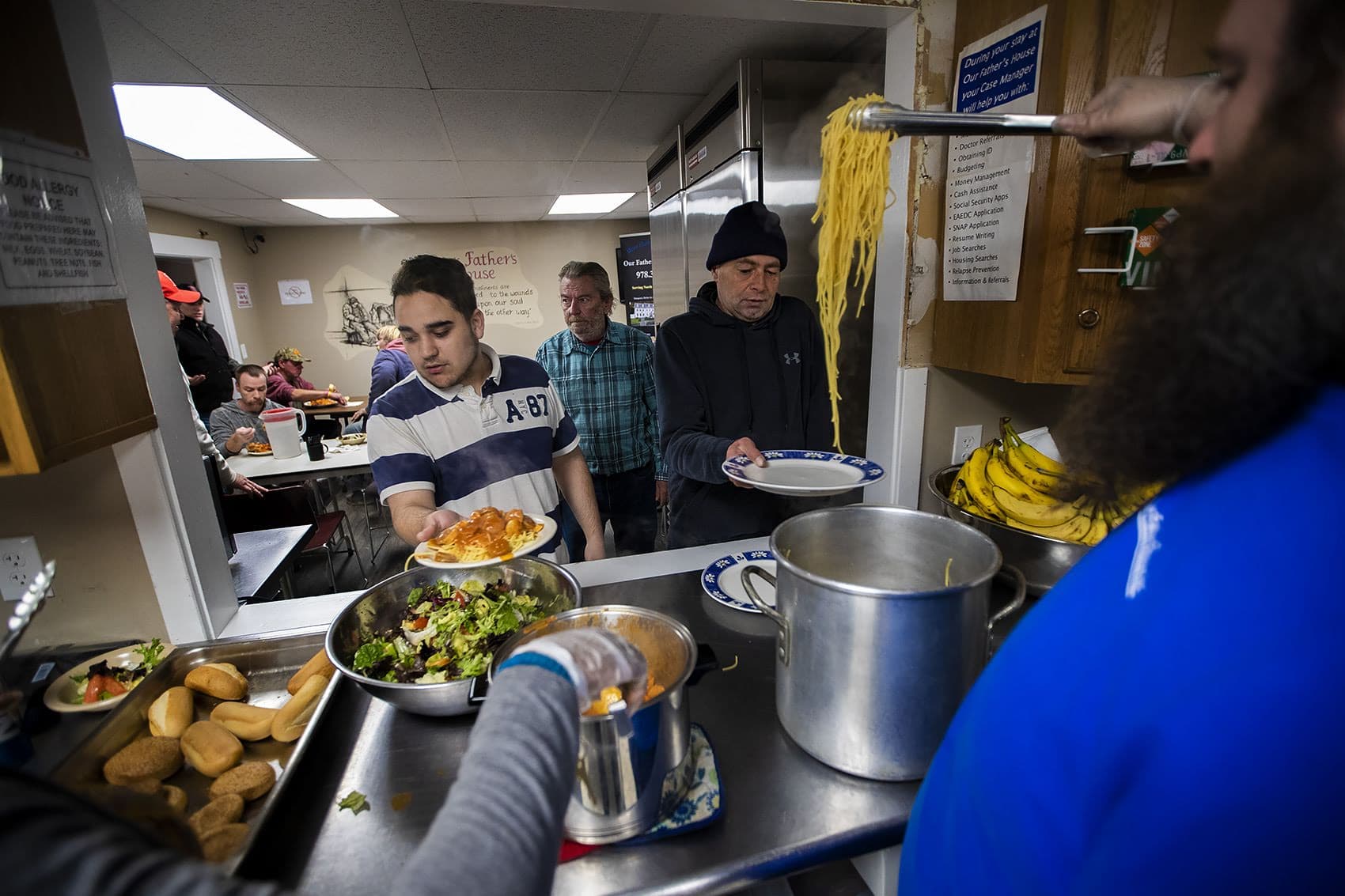 Guests recieve a spaghetti dinner at Our Father’s House in Fitchburg. (Jesse Costa/WBUR)