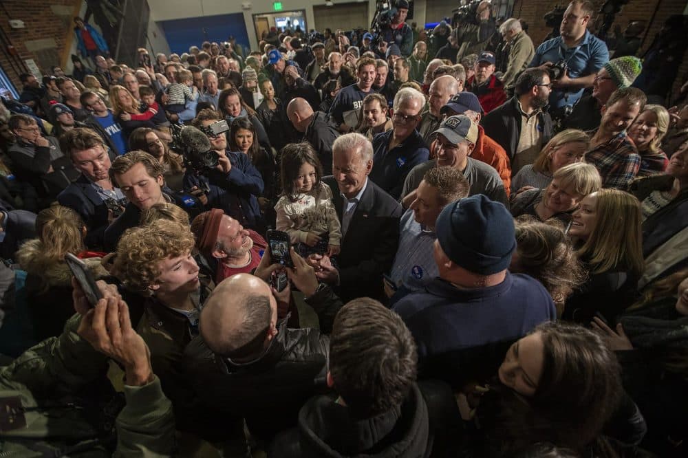 Presidential candidate Joe Biden poses for a photo with a young girl in his arms at a campaign rally at the Rex Theater in Manchester, NH. (Jesse Costa/WBUR)