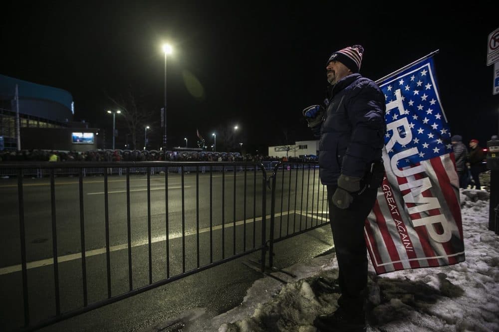 Nathan Legacy, of Manchester, watches a screen before President Donald Trump speaks at Southern New Hampshire University Arena. (Jesse Costa/WBUR)