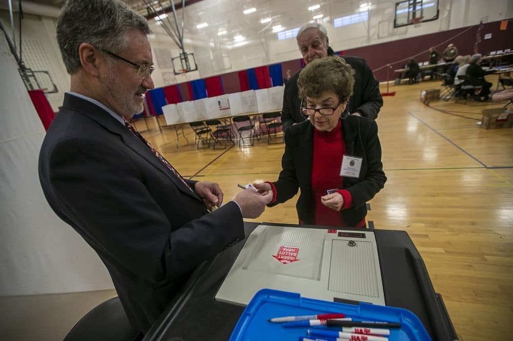 William Tucker passes out “I Voted” sticker after people finish voting at Portsmouth Middle School. (Jesse Costa/WBUR)