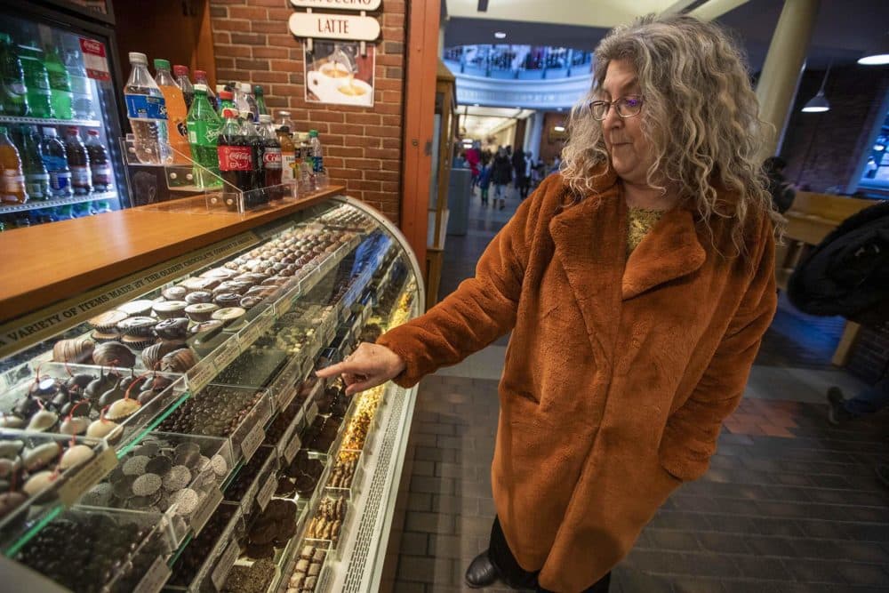 Susan Benjamin points out the different varieties of chocolates in a display case at Quincy Market. (Jesse Costa/WBUR)
