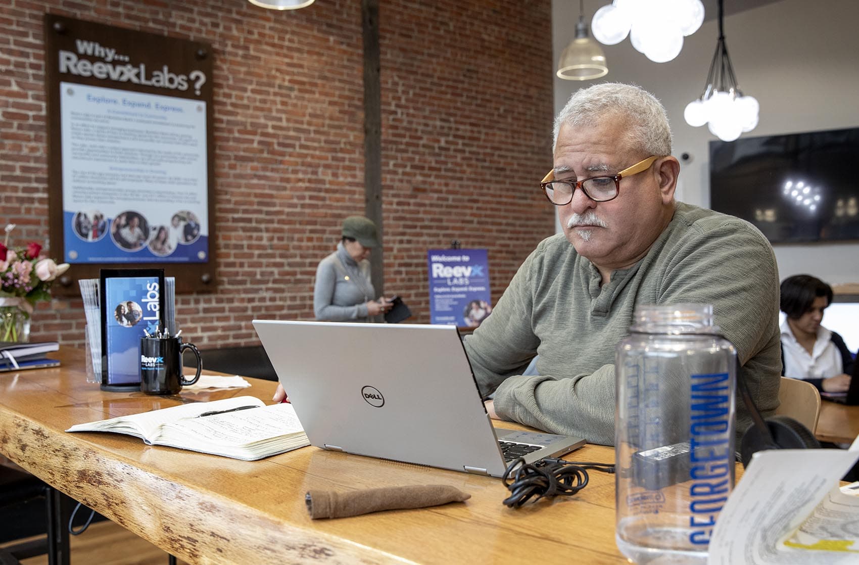 Sitting by the window at Reevx, Wayne Ysaguirre works on plans to launch a new non-profit. He says it's a good place to focus and get work done. (Robin Lubbock/WBUR)