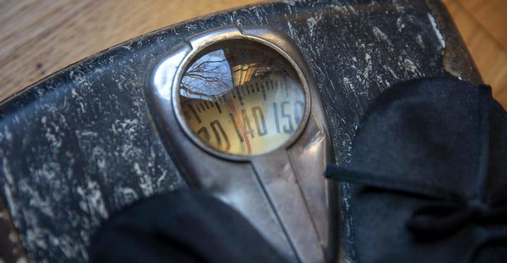 A person stands on an old body weight scale. (Robin Lubbock/WBUR)