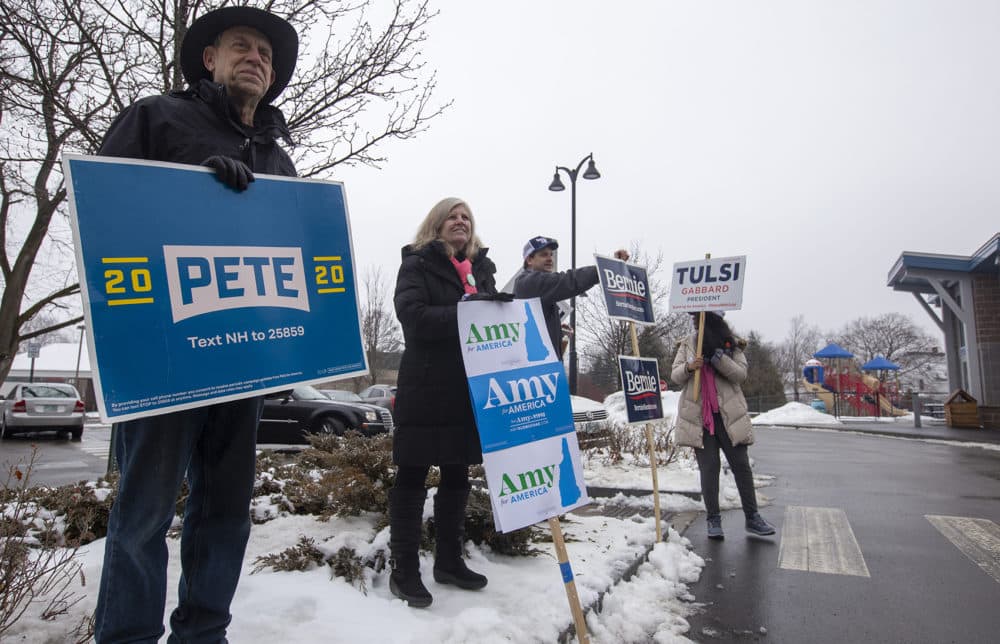 Rob Fried, Candace Bouchard and Nate Shurtleff, all of Concord, N.H., and Sheila Chaudary, of Queens, N.Y., hold signs outside of a polling place in Concord, N.H. (Joe Difazio for WBUR)