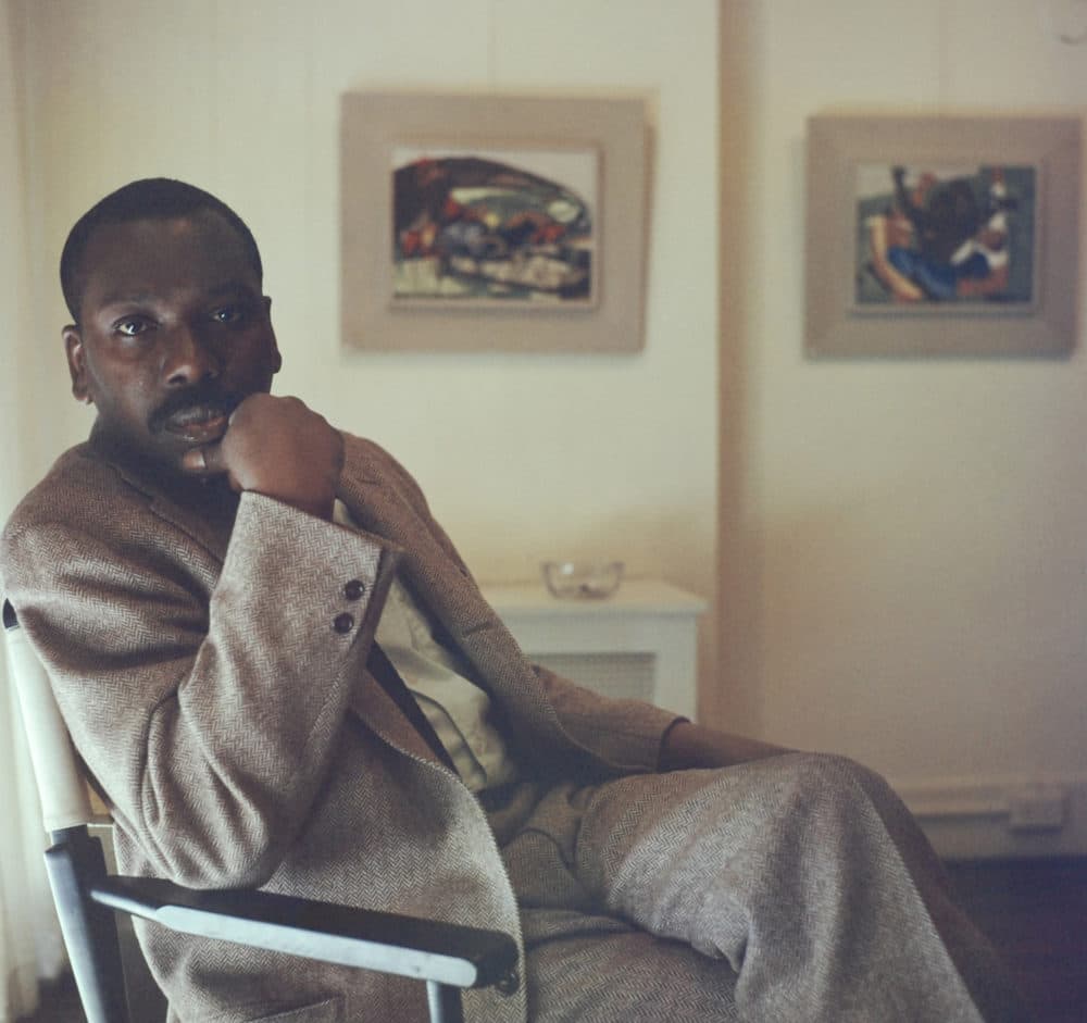 Artist Jacob Lawrence sitting in front of some of his paintings. (Courtesy Robert W. Kelley/The LIFE Picture Collection via Getty Images)