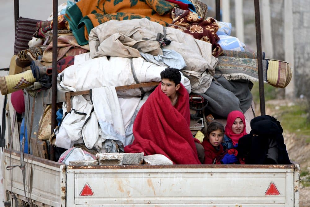 People ride in the back of a truck with furniture, mattresses, and blankets while passing by an internally-displaced persons (IDP) camp near the Turkish border in the west of Syria's northern province of Aleppo on Feb. 16, 2020, fleeing advancing Syrian government forces in Idlib and Aleppo provinces. (Rami al Sayed/AFP/Getty Images)
