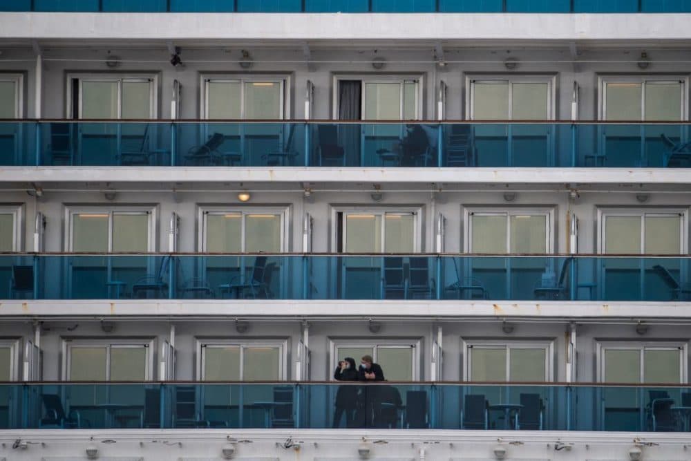 Passengers wearing face masks look out from their cabin on the Diamond Princess cruise ship in quarantine due to fears of COVID-19. (Philip Fong/AFP/Getty Images)