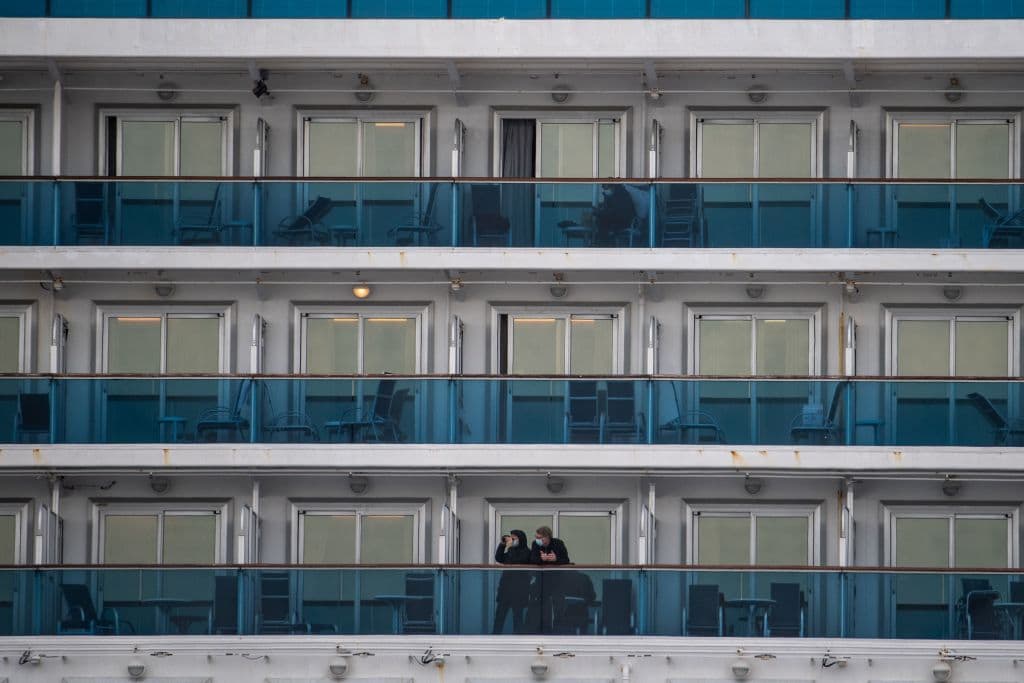 Passengers wearing face masks look out from their cabin on the Diamond Princess cruise ship in quarantine due to fears of COVID-19. (Philip Fong/AFP/Getty Images)