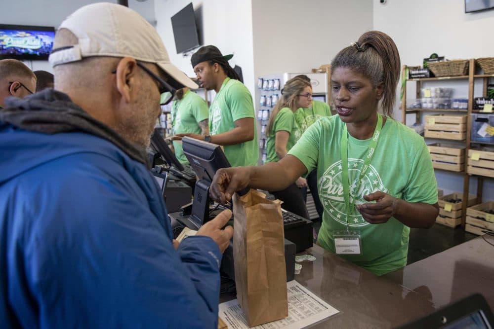 Oasis staff member Renee Cox makes a sale on the first day of business at the store. (Robin Lubbock/WBUR)