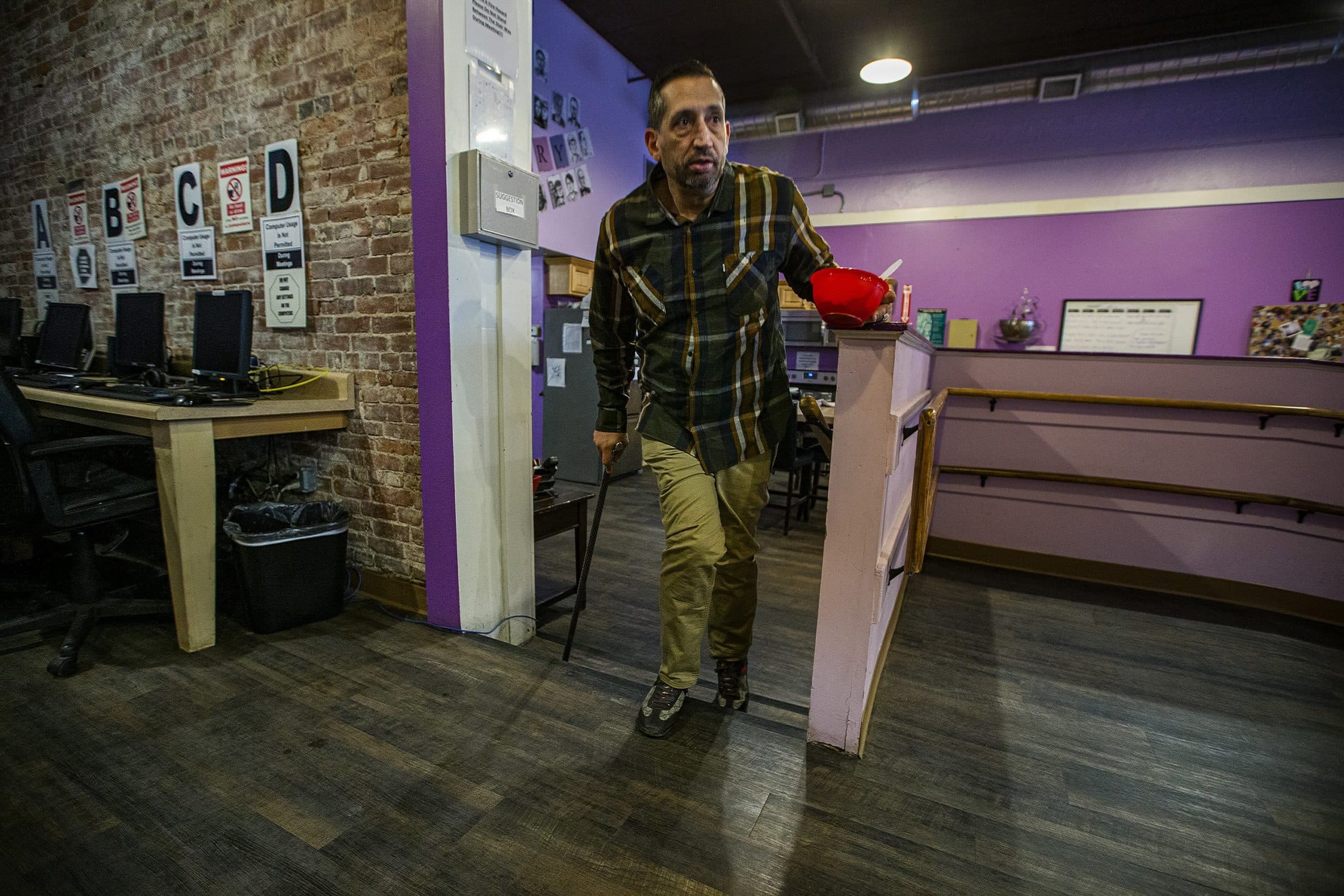 Walking with a cane, Michael Earielo climbs the stairs at a drug recovery center he manages in Worcester. (Jesse Costa/WBUR)