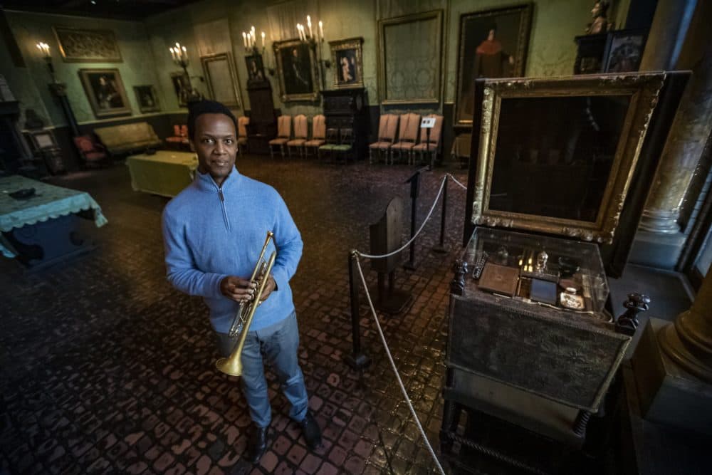 Trumpeter, composer and educator Jason Palmer stands beside the empty frame of Vermeer’s “The Concert” in the Dutch Room at the Isabella Stewart Gardner Museum. He has composed and recorded 12 pieces of music inspired by the Gardner Museum heist which happened 30 years ago. (Jesse Costa/WBUR)
