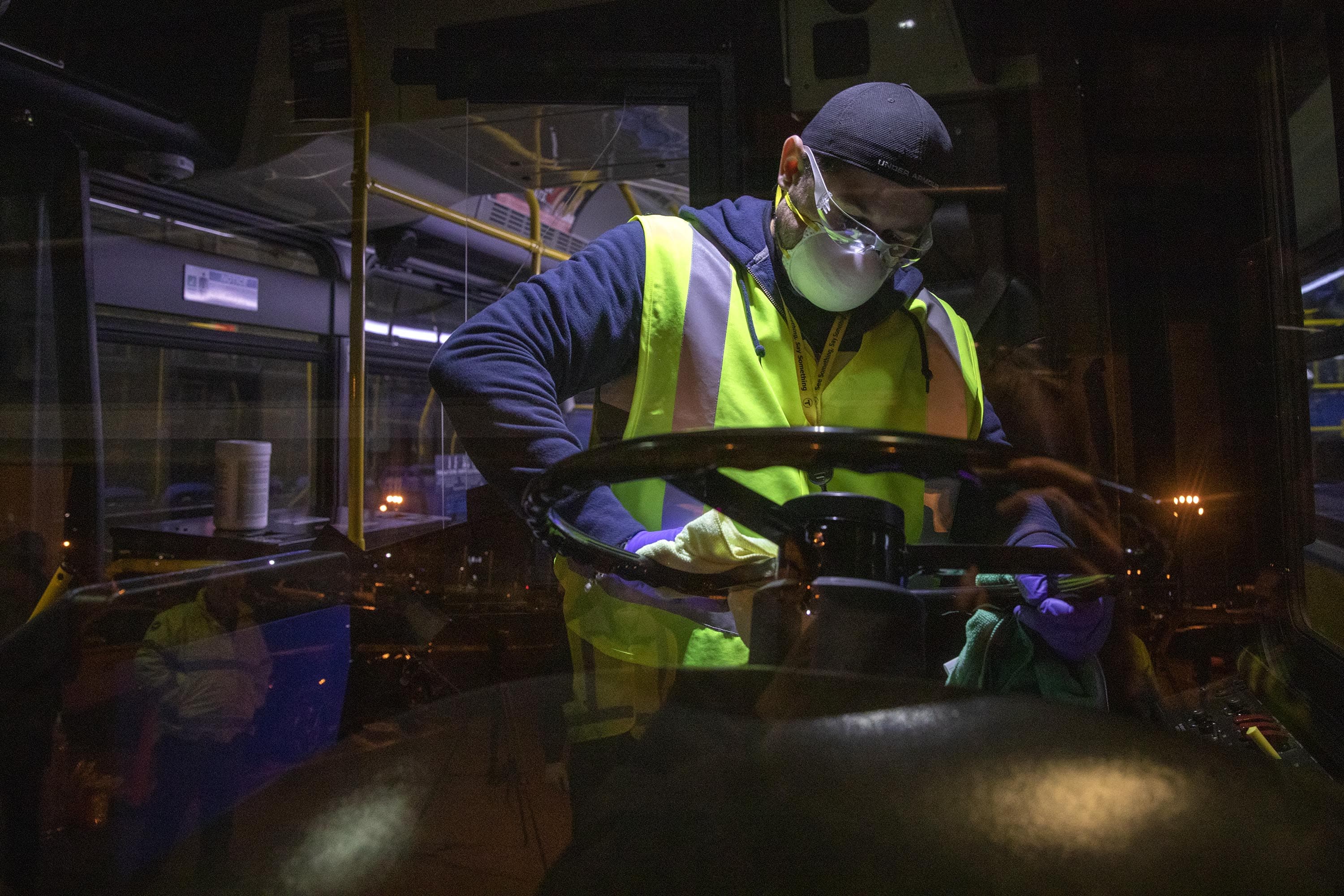 The MBTA’s Fradwin Suarez wipes down the steering wheel of the bus overnight at the Charlestown bus garage. (Robin Lubbock/WBUR)