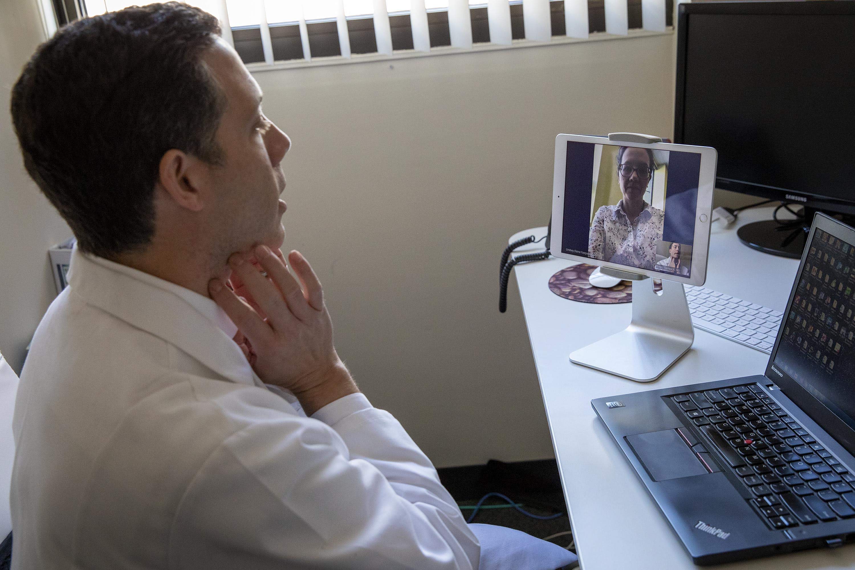 Dr. Philip Ciampa, left and in the bottom screen, shows a colleague, at the top of the screen, how to ask a patient to do simple self-examination tasks, in a demonstration of a “virtual visit.” (Robin Lubbock)