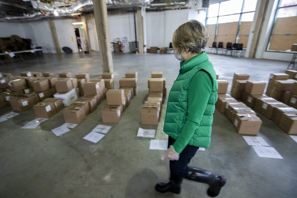 A worker examines bobxed up course material for each student to resume their coursework for the next two weeks with the Chomebook they will receive. (Jesse Costa/WBUR)