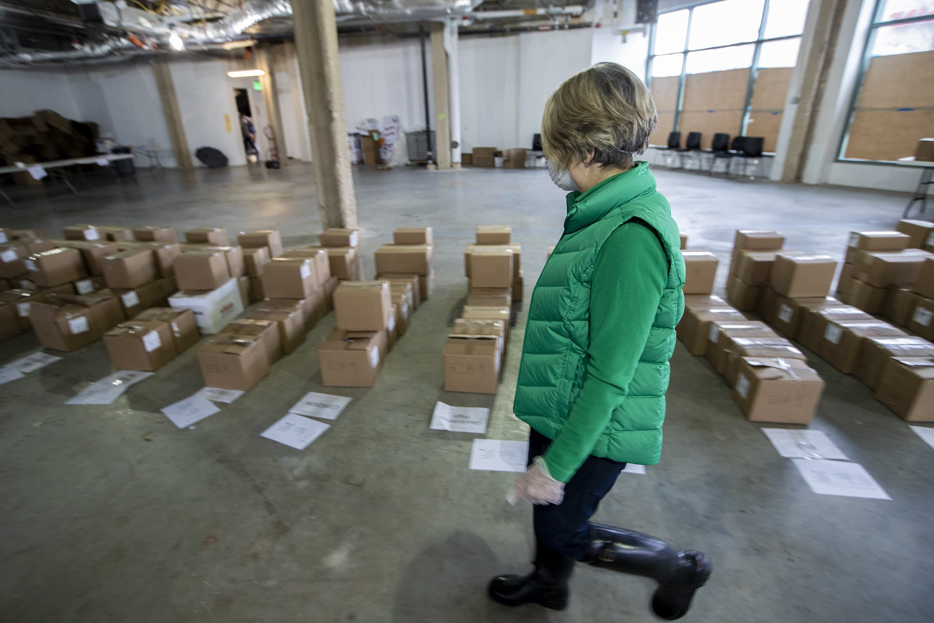 A worker examines boxed up course material for each student to resume their coursework for the next two weeks with the Chomebook they will receive. (Jesse Costa/WBUR)