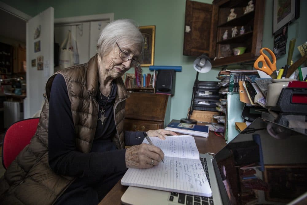 Jane Poncia writes in a notebook in her office at her home in East Boston. (Jesse Costa/WBUR)