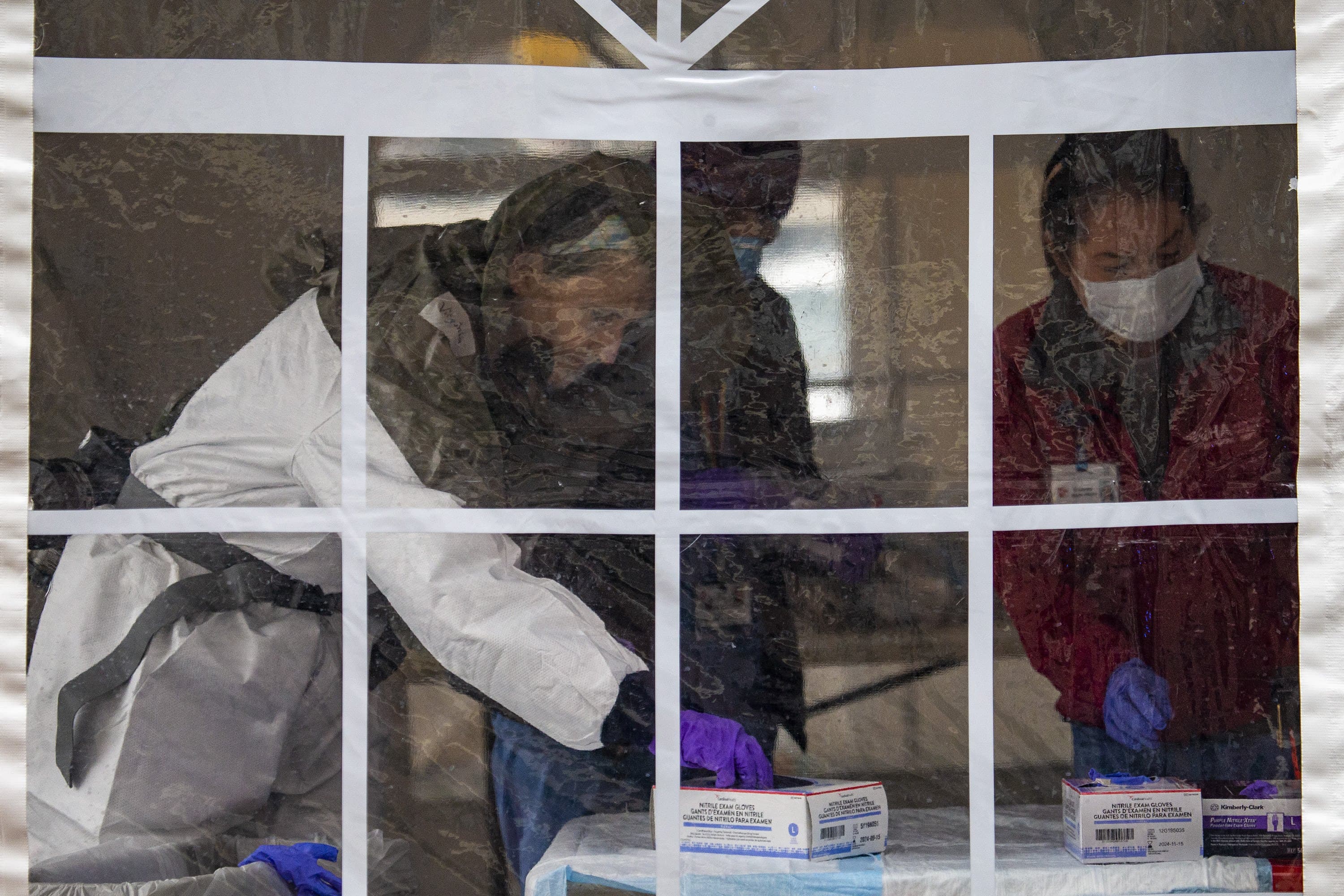 Health care workers in a tent prepare to test the next person at a drive-through area for COVID-19 testing at Somerville Hospital. (Jesse Costa/WBUR)