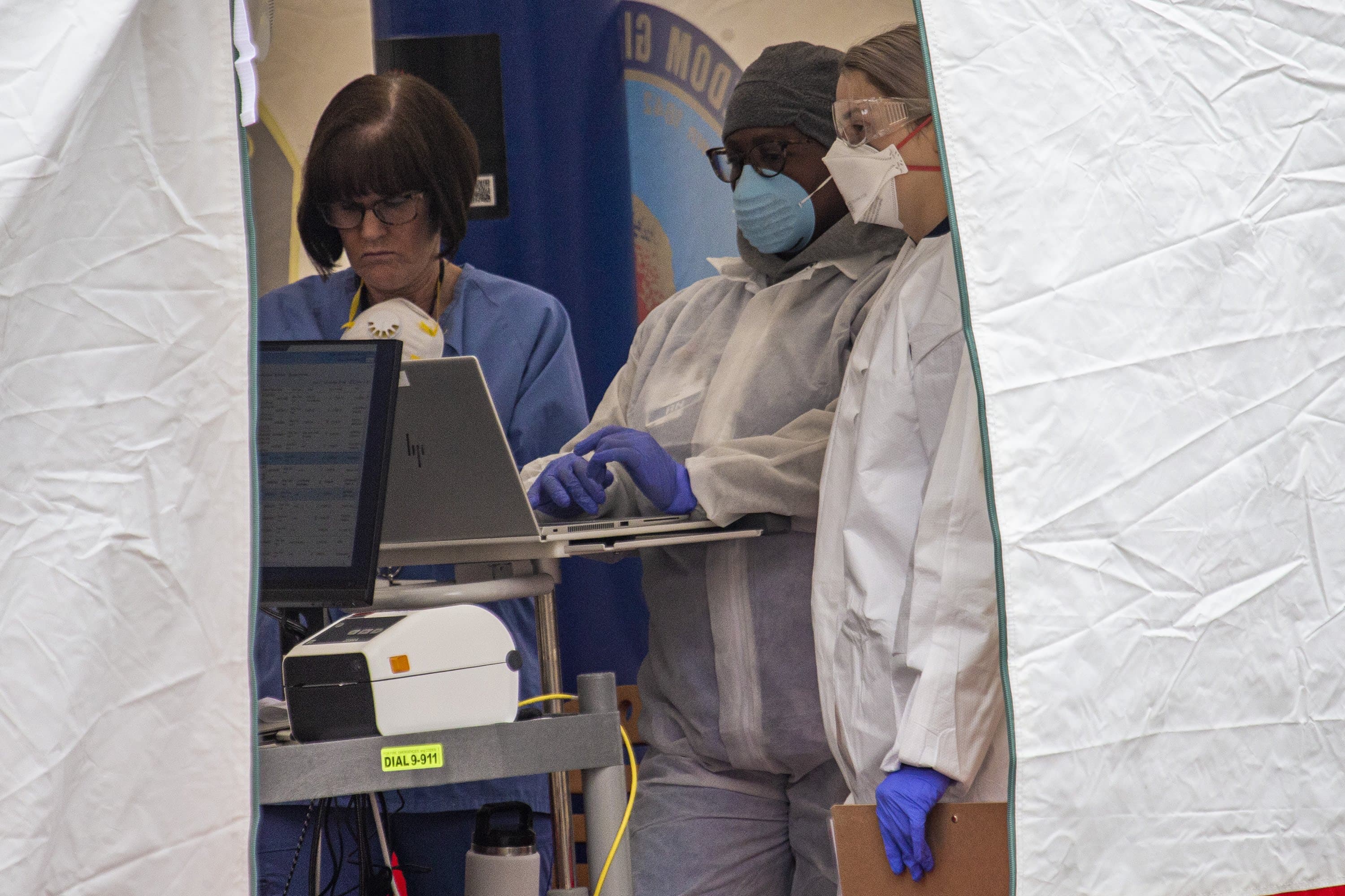 Health care workers register people being tested in a tent at a drive-through area for testing COVID-19 at Somerville Hospital. (Jesse Costa/WBUR)