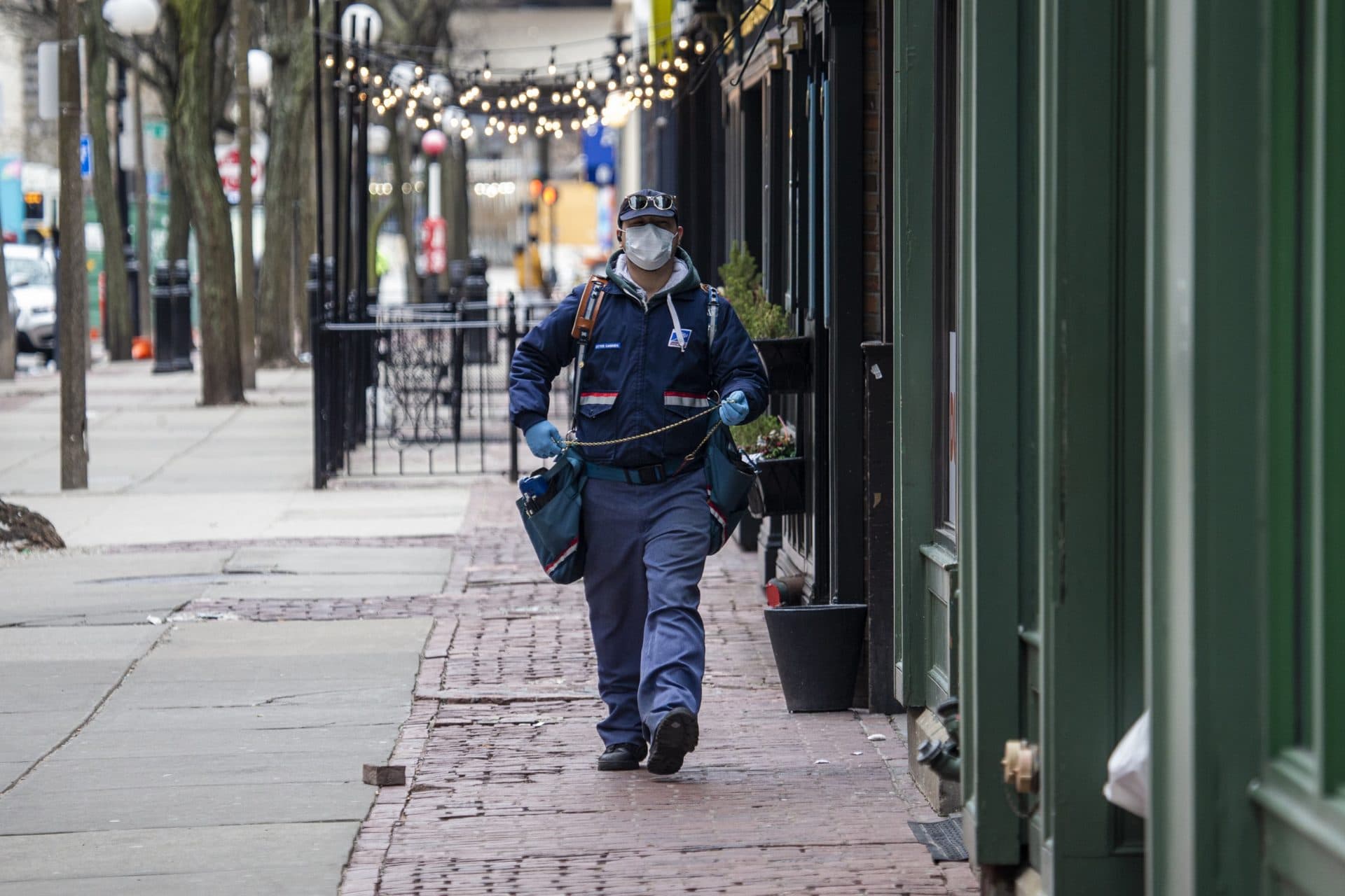 March 23: A U.S. postal mail carrier with a mask delivers mail on Canal Street by North Station. (Jesse Costa/WBUR)