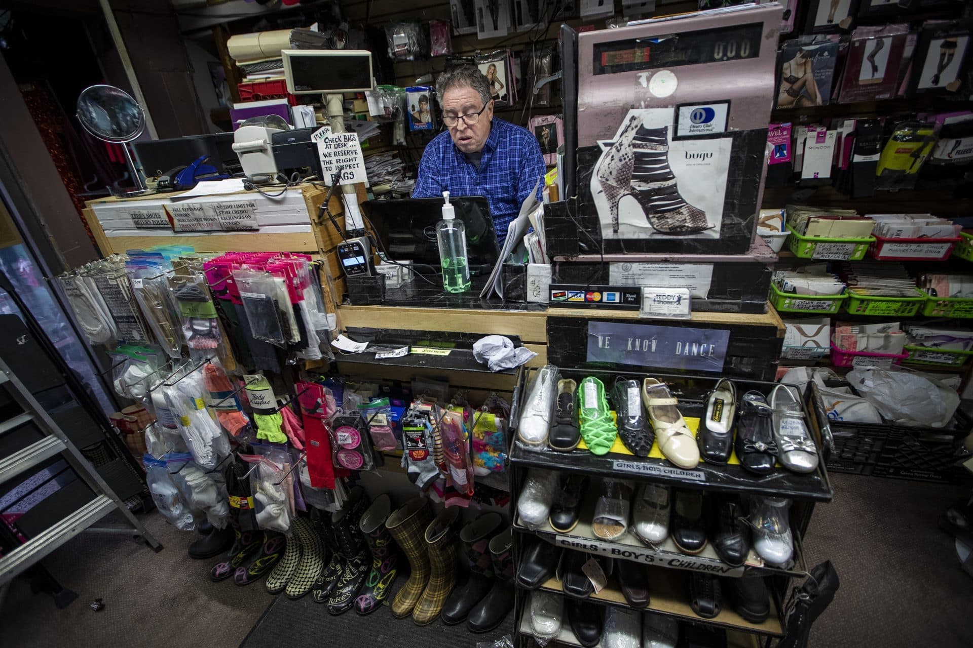 March 23: Teddy’s Shoes owner Steven Adelson sits behind the counter of his store, working on a GoFundMe page. He hopes with the combination of online sales and donations he receives, he will be able to keep his business. (Jesse Costa/WBUR)
