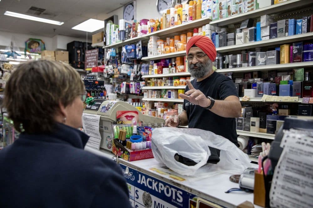 Harsimrat "Harry" Singh, owner of the J&M Dollar Store on Moody Street, chats with the Rev. Rebecca Sheble-Hall as she makes a purchase. (Robin Lubbock/WBUR)